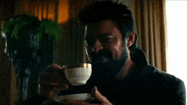 a man with a beard is drinking from a cup of tea .
