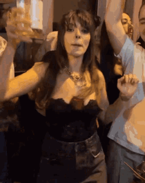 a woman in a black top is holding a beer in her hand