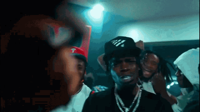 a man wearing a hat with the letter t on it is surrounded by other men