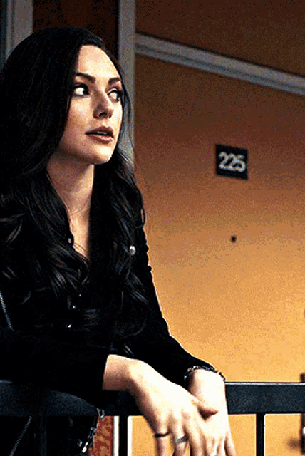 a woman is leaning on a railing in front of a door with the number 225 on it