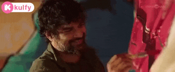 a man with a beard is smiling while looking at a woman in a red dress .