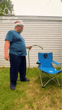 a man wearing a mask is holding a hose in front of a blue chair