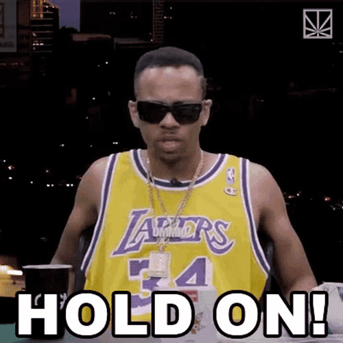 a man wearing a lakers jersey and sunglasses is saying hold on