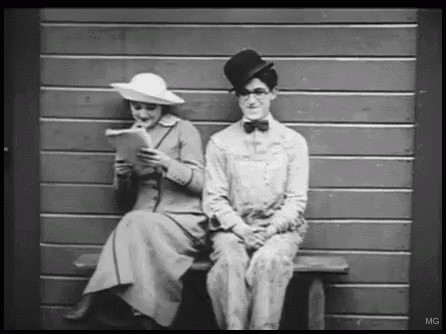 a man and a woman are sitting on a bench in front of a wall .