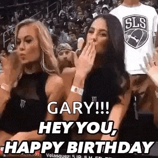 two women are sitting in the stands of a basketball game and one of them is blowing a kiss .