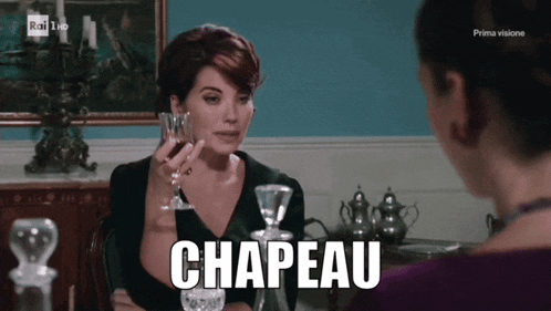 a woman sitting at a table with a glass of wine and the word chapeau
