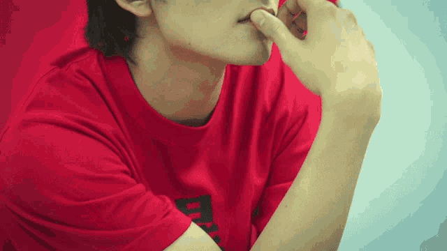a man wearing a red shirt with a black letter d on it