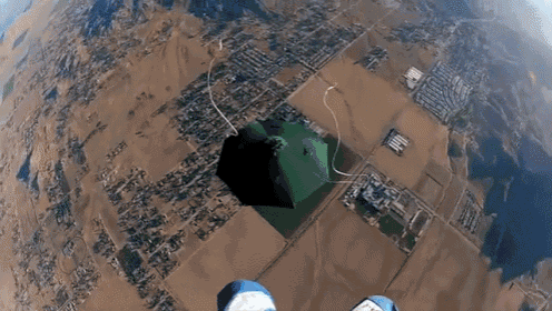 a person is flying through the air with a green pyramid behind them