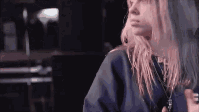 a woman with long blonde hair is wearing a blue shirt