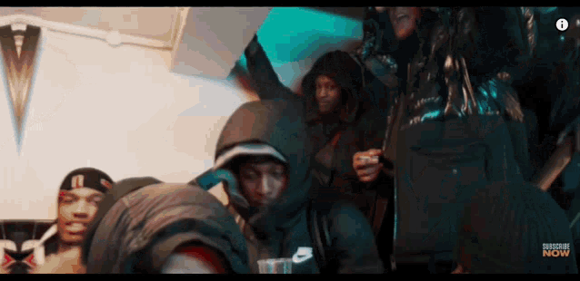 a group of people are gathered in a room with the word now on the bottom left