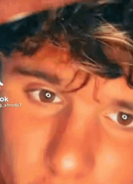 a close up of a young man 's eyes with a red background