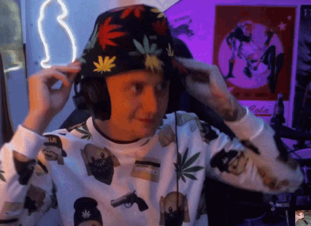 a man wearing a hat with marijuana leaves on it adjusts his headphones