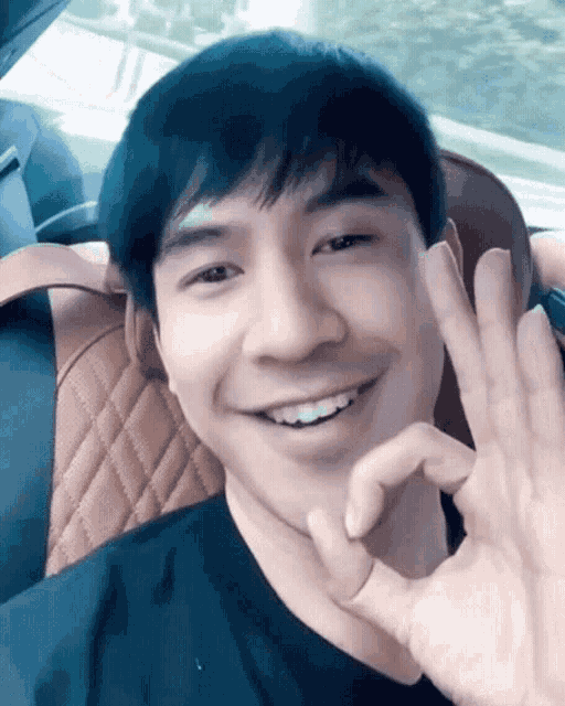 a man in a black shirt is smiling and making an ok sign