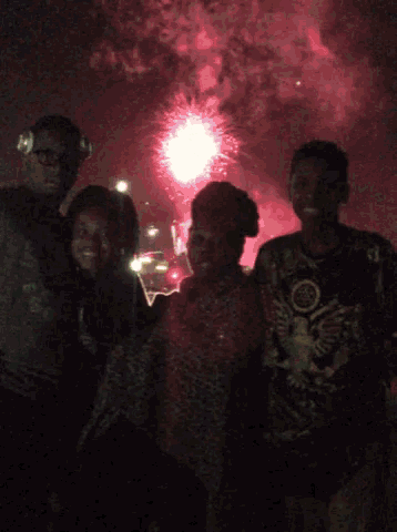a group of people are posing for a picture in front of fireworks