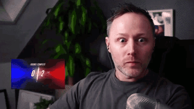 a man is sitting in front of a screen that says round 1 complete on it