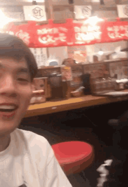 a man in a white shirt is smiling in front of a sign that says ' coca cola ' on it
