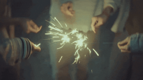 a group of people holding sparklers in their hands in the dark
