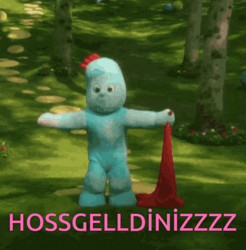 a blue teddy bear is standing in a garden with the words hossgeldinizzz on the bottom right