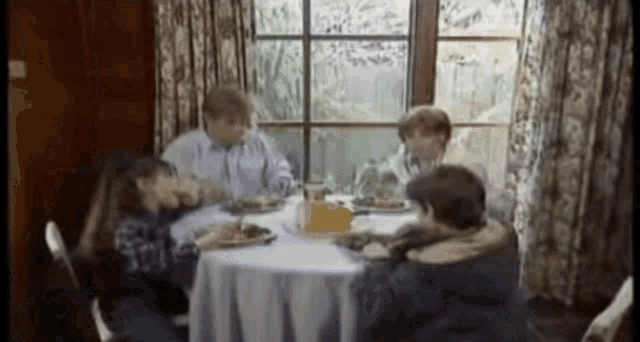 a group of people are sitting around a table eating