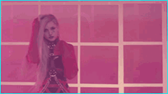 a woman with long pink hair is standing in front of a pink wall .