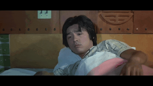 a man laying on a bed with a chinese symbol on the wall