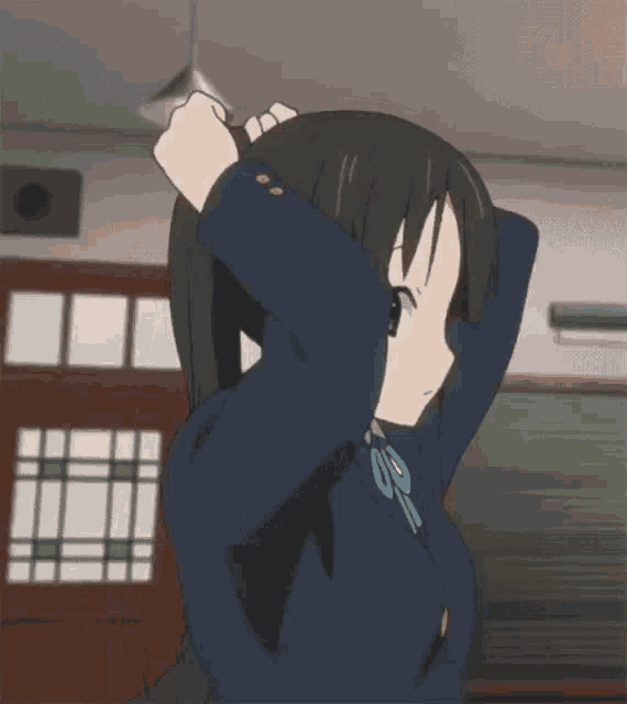 a girl in a school uniform is tying her hair into a ponytail