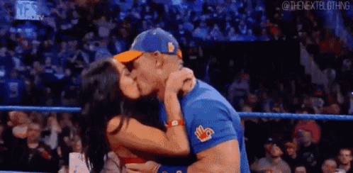 a man and a woman kissing in a wrestling ring .