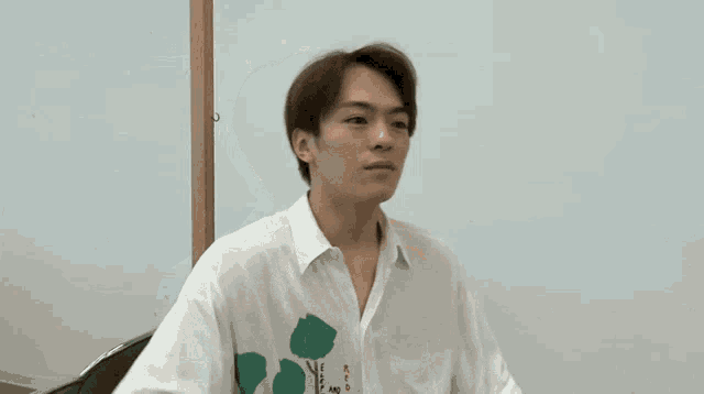 a young man in a white shirt with a green flower on it is holding a sign that says chu