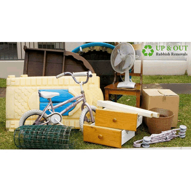 a bunch of rubbish including a bicycle and a fan with a up & out rubbish removals logo