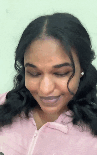 a close up of a woman 's face with her eyes closed and a pink shirt on