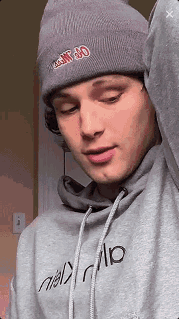 a young man wearing a gray hoodie and a gray beanie