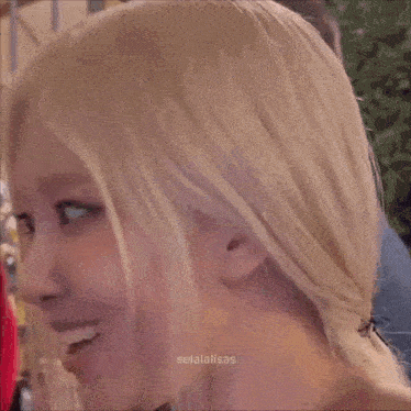 a close up of a woman with blonde hair and a man in the background .