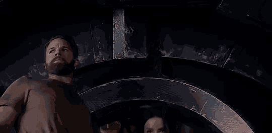 a man and a woman are standing next to each other in a dark room in a movie .