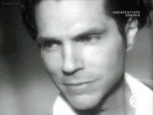 a black and white photo of a man in a white shirt looking at the camera .