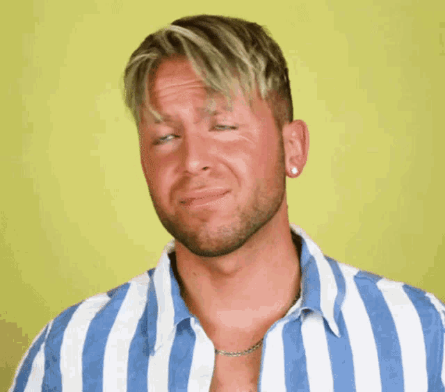 a man wearing a blue and white striped shirt making a funny face