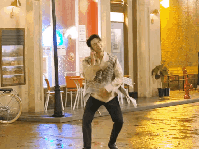 a man is dancing in front of a building with a sign that says ' ice cream ' on it