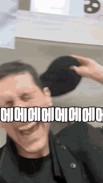 a man is laughing while someone holds a hat over his head with the words " cicicicicicicici " written on it