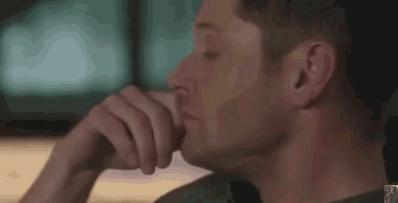 a man is sitting at a table with his hand on his chin and looking down .