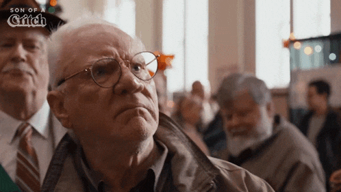 an older man wearing glasses stands in front of a sign that says son of a glick
