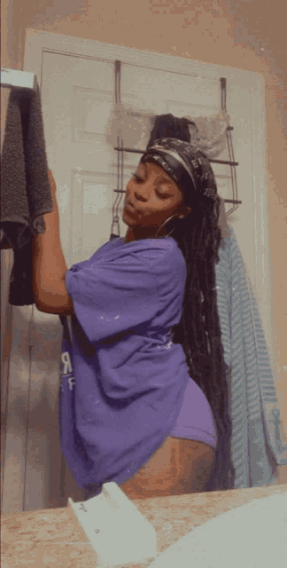 a woman in a purple shirt with the letter f on it holds a towel over her head