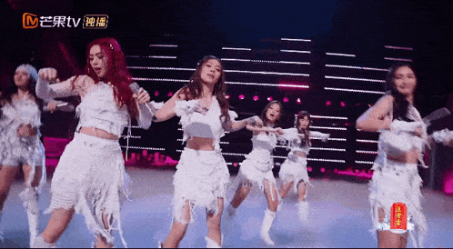 a group of women are dancing on a stage in front of a sign that says tv on it