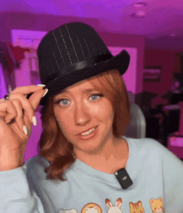 a woman wearing a top hat and a blue sweater with animals on it