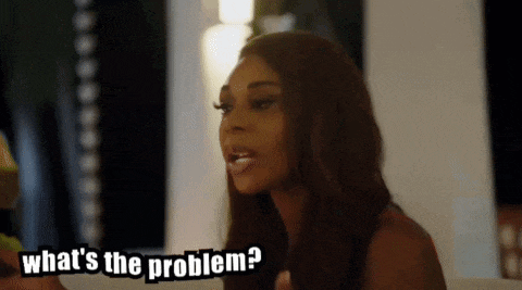 a woman is sitting on a couch talking to someone and asking what 's the problem ?