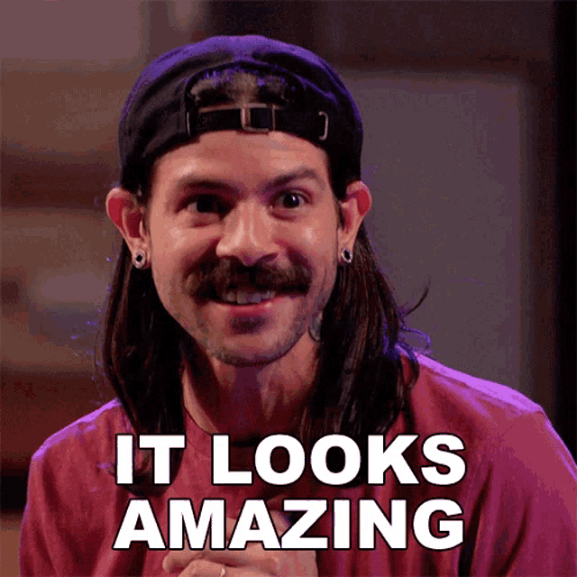 a man with long hair and a hat is smiling with the words it looks amazing behind him
