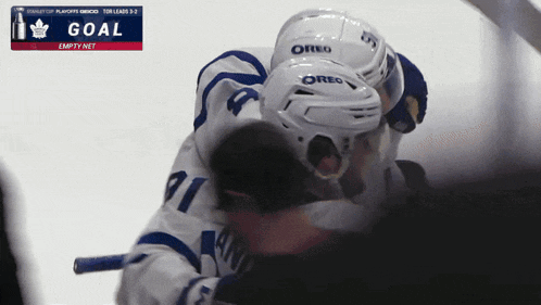 a hockey player wearing an oreo helmet hugging another player