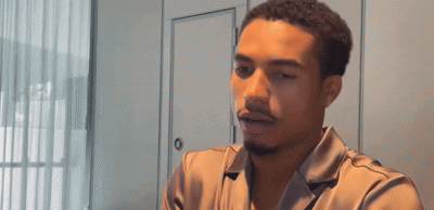 a man with a beard wearing a satin shirt looks at the camera