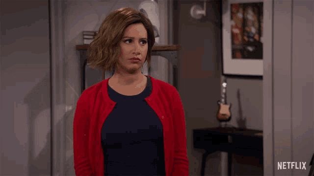 a woman in a red cardigan stands in front of a netflix ad