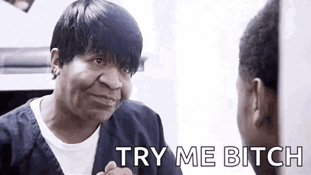 a man is looking at himself in a mirror with the words `` try me bitch '' .