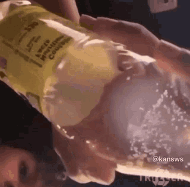 a person is pouring a bottle of lemonade into a container .