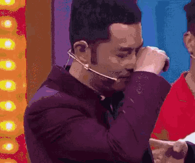 a man with a microphone around his neck is covering his eyes